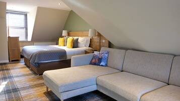 A bedroom with a bed, a sofa, a radiator, and a window with blinds.