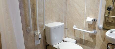 A modern bathroom with a toilet, grab bars, a hand dryer, and a sink.