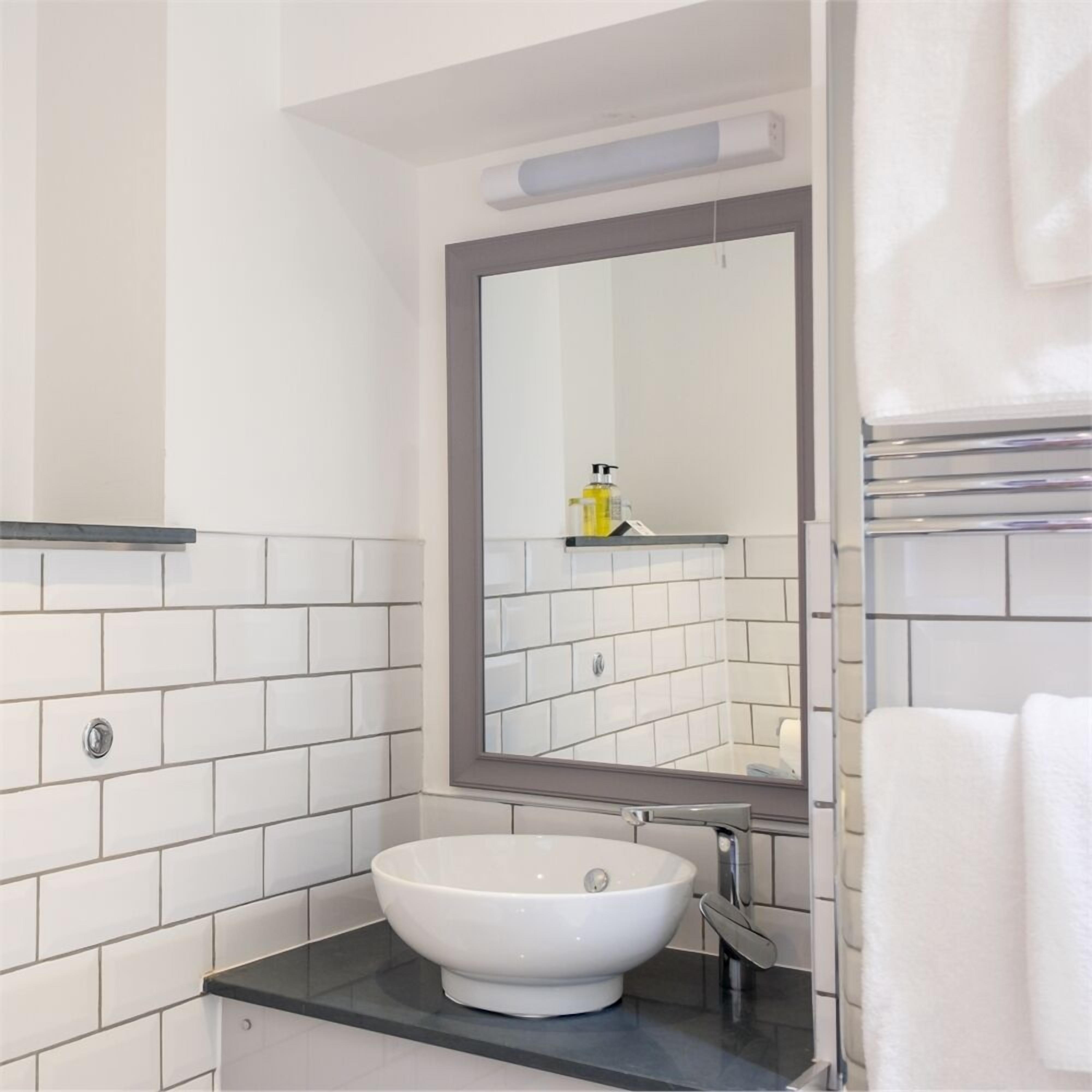 A bathroom with a white sink, a mirror, and a towel rack.