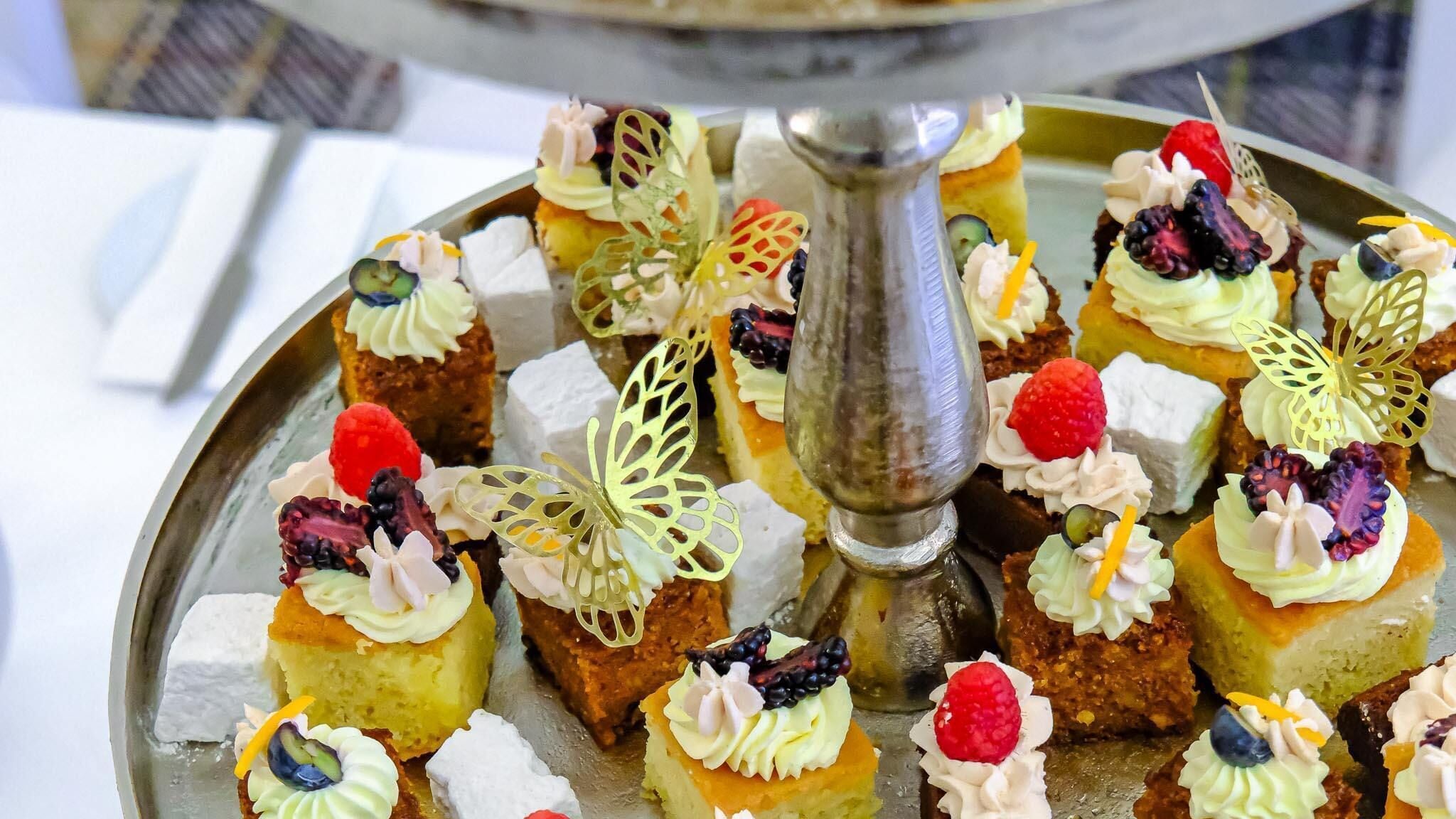 A tray of assorted desserts with decorative elements like leaves and berries.