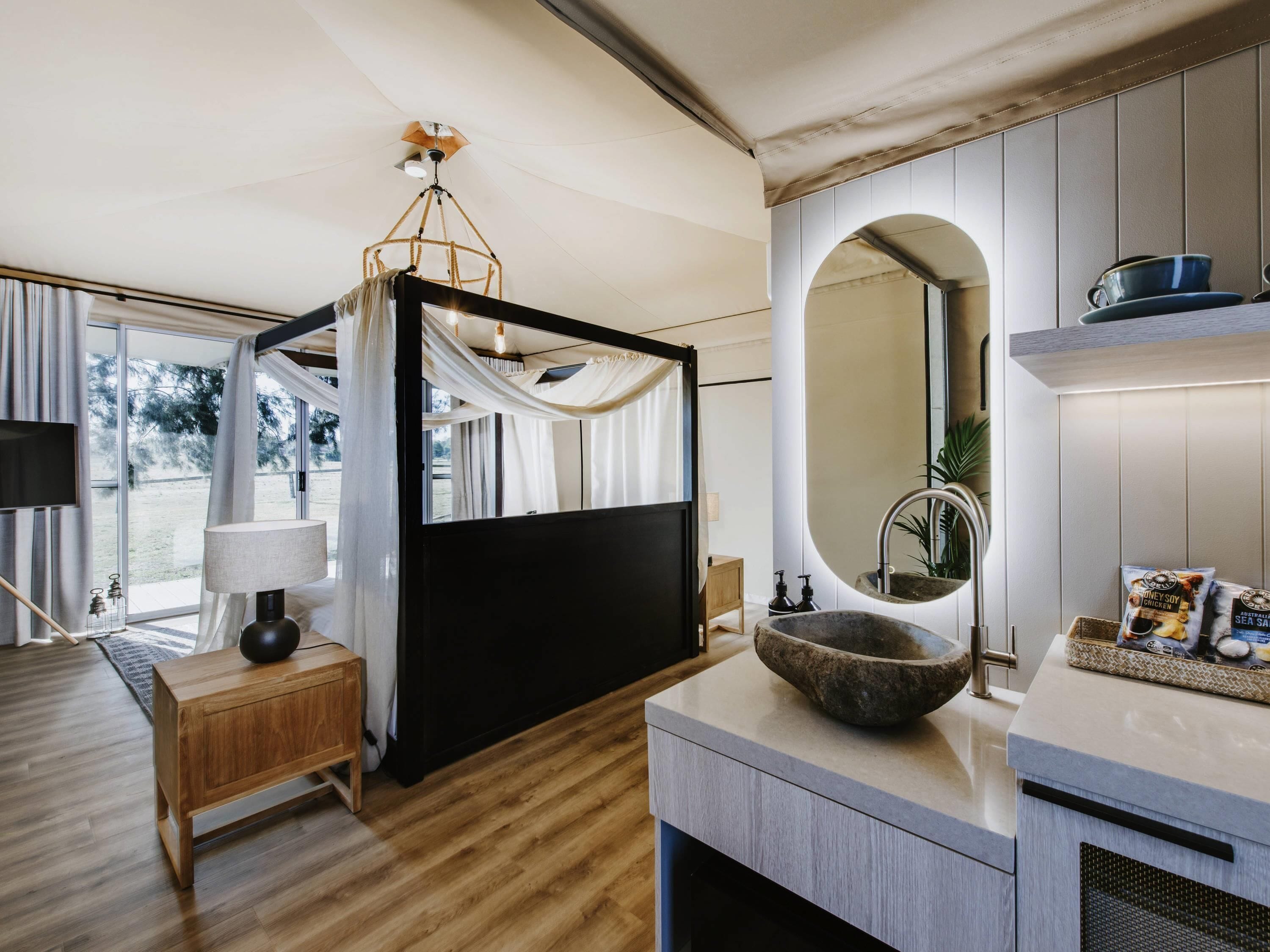 Une salle de bain moderne avec un lavabo en pierre, un grand miroir et un meuble-lavabo en bois.