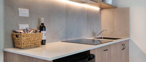 A modern kitchen with a built-in dishwasher, a wine bottle, and a wicker basket on the countertop.