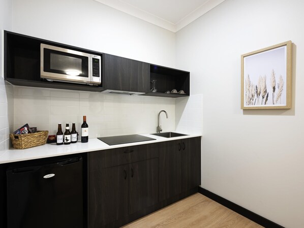 Una cocina moderna con armarios oscuros, microondas, fregadero y lavavajillas.