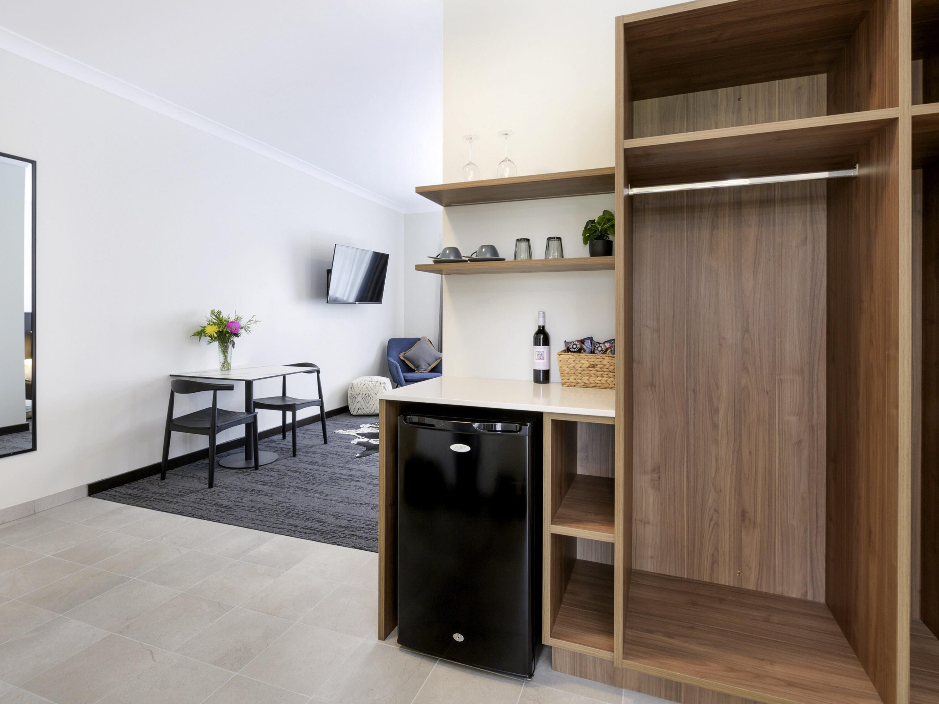 A compact living space with a kitchenette, a dining area, a seating area, and a built-in wardrobe.