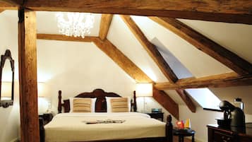 Ein Schlafzimmer mit einem großen Bett, Holzbalken, einem Chandelier und einem Oberlicht.