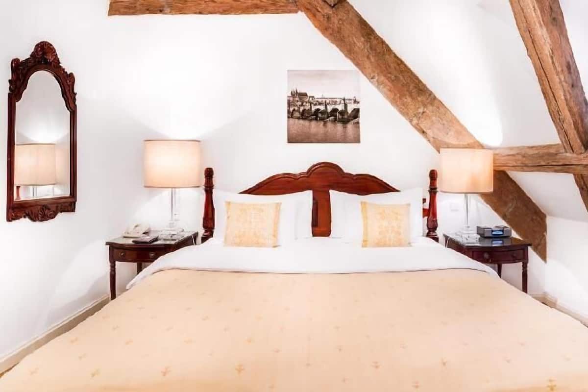 A bedroom with a large bed, wooden headboard, two bedside tables with lamps, a mirror, and a framed picture on the wall.