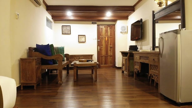 Un salon avec un canapé en bois, une table basse, un meuble en bois et un téléviseur.