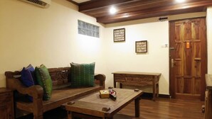 Une pièce au plancher de bois, avec un canapé, une petite table et une porte.