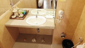 Un baño con dos lavamanos, un espejo, un secador de pelo y artículos de aseo en la encimera.