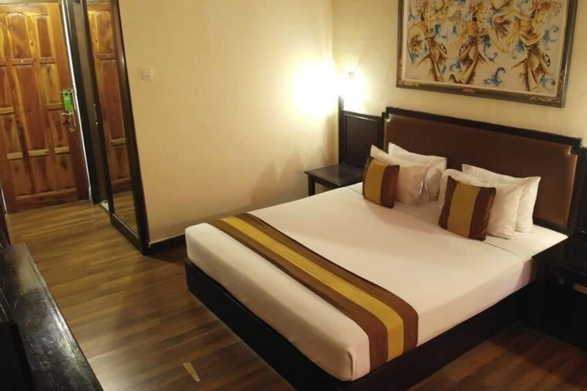 Ein Hotelzimmer mit einem großen Bett, Holzboden, zwei Nachttischen und einem Bild an der Wand.