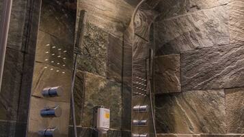 A modern shower with multiple spray heads and a control panel.