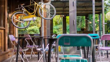 A patio area with a yellow bicycle hanging on a metal pole, surrounded by folding chairs and tables.
