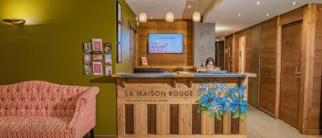 A reception desk with a wooden design, a television screen above it, and a chair to the left.