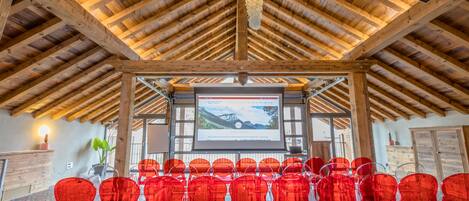 A conference room with a wooden ceiling and a projection screen displaying a scenic image.