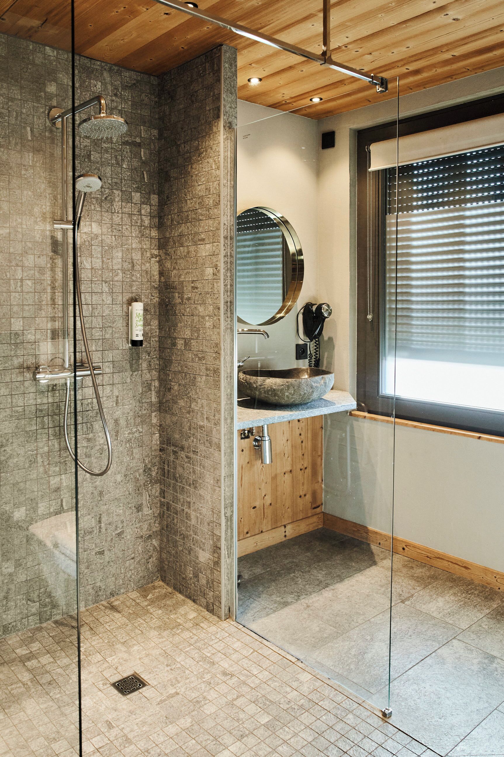 Un baño moderno con cabina de ducha de vidrio, tocador de madera y un espejo grande.