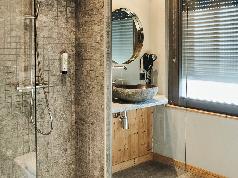 Un baño moderno con cabina de ducha de vidrio, tocador de madera y un espejo grande.