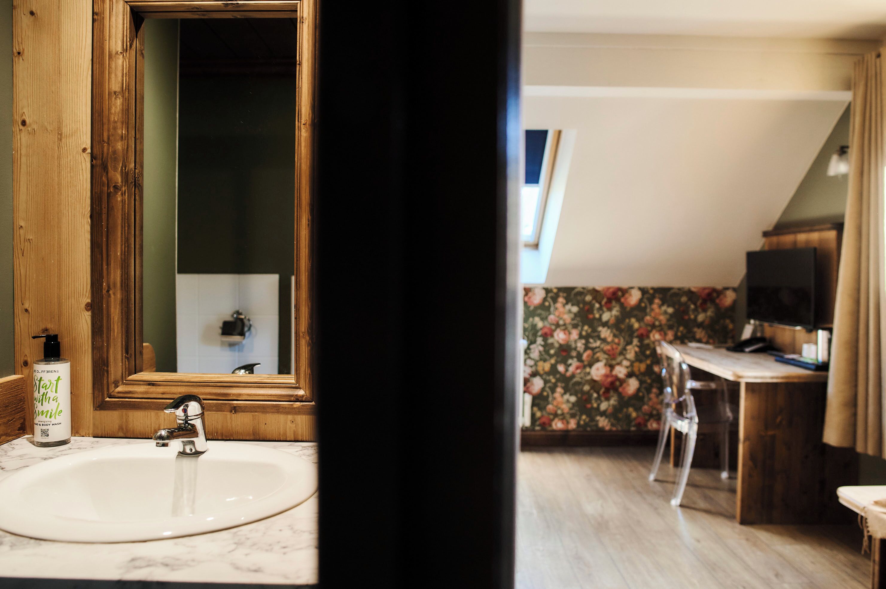 A bathroom with a wooden vanity, a white sink, and a mirror.