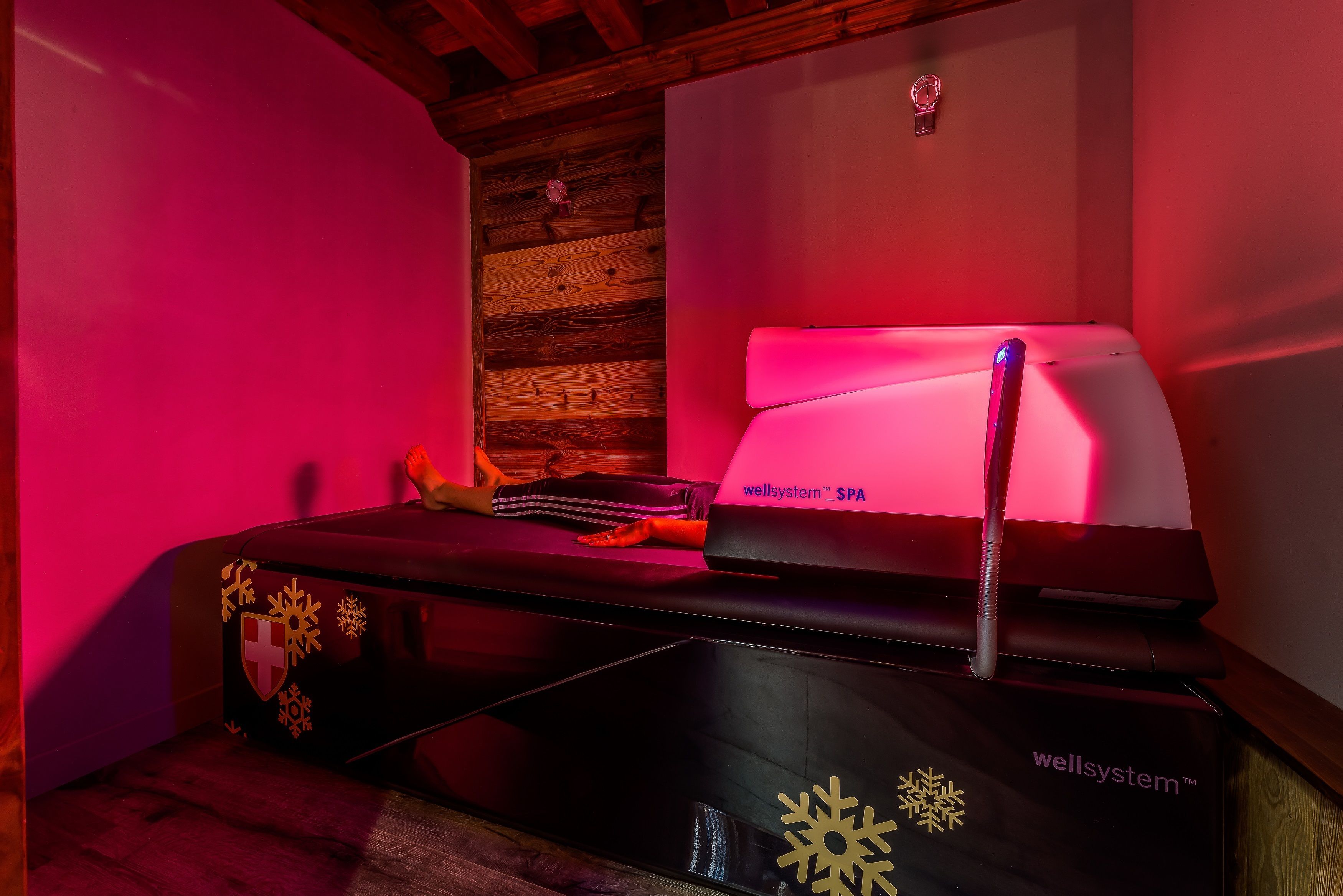 A spa bed with a massage chair, a logo, and a wooden wall.
