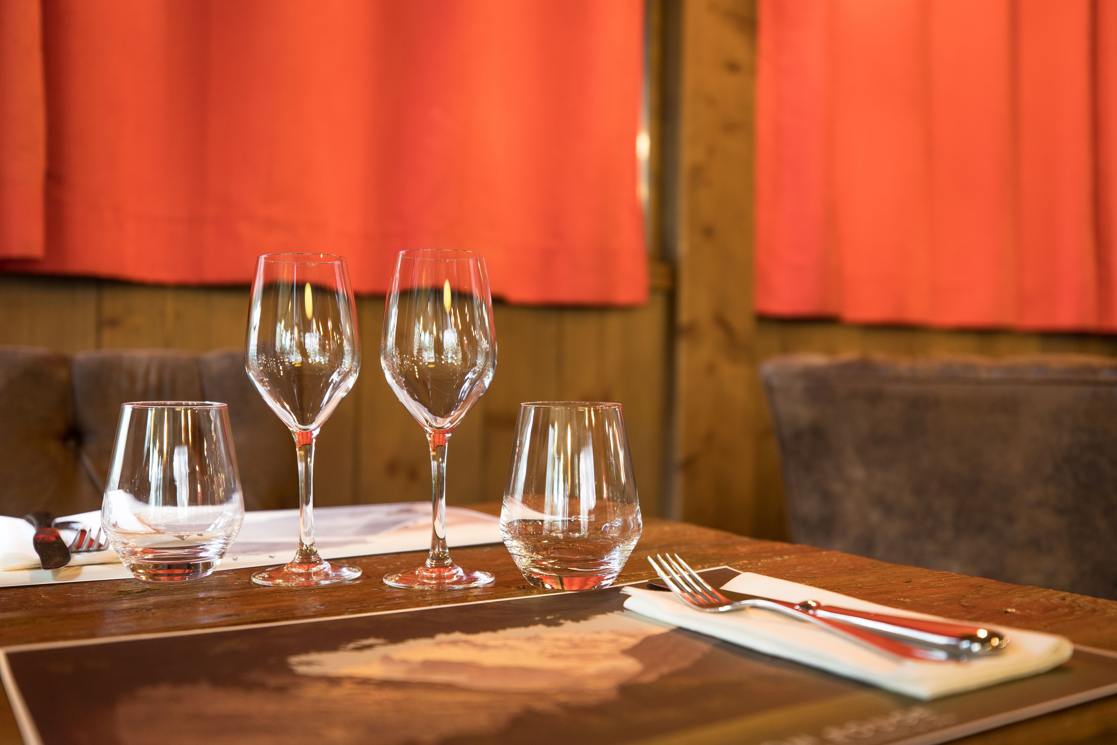 Una mesa con tres copas de vino y cubiertos.