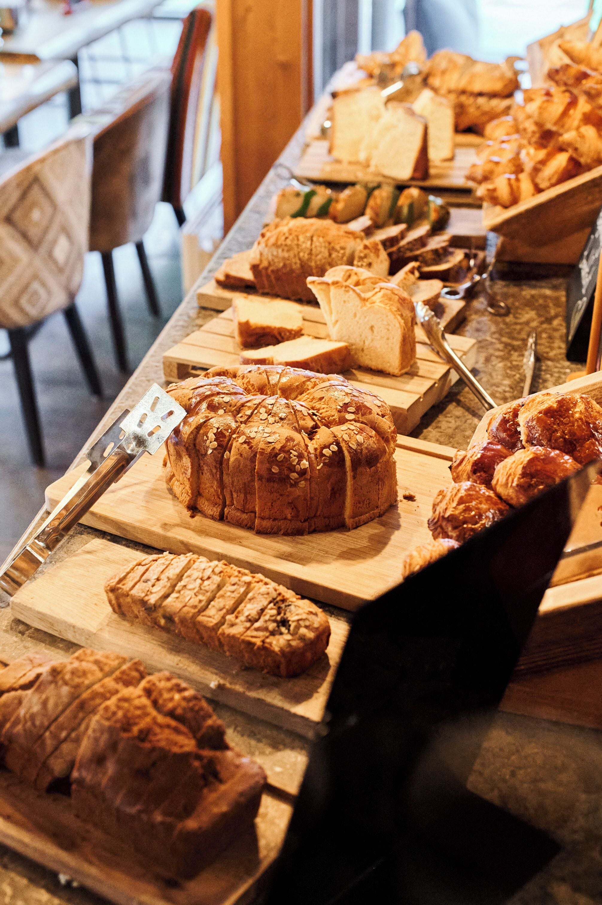 Une variété de pains et de viennoiseries présentés sur des planches à découper en bois.