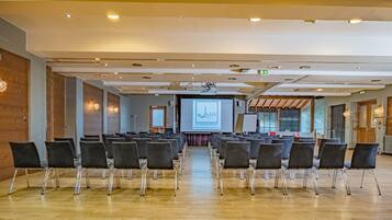 A conference room with rows of chairs facing a projection screen displaying a logo and text.