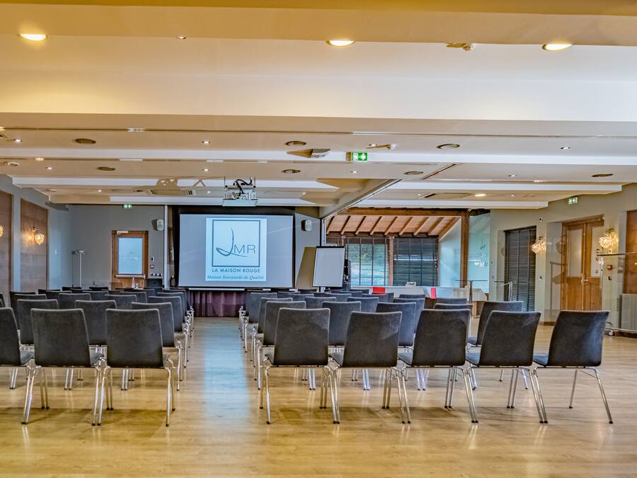 A conference room with rows of chairs facing a projection screen displaying a logo and text.