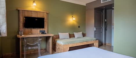 A bedroom with a bed, a wooden desk, a television, and two wall-mounted lights.