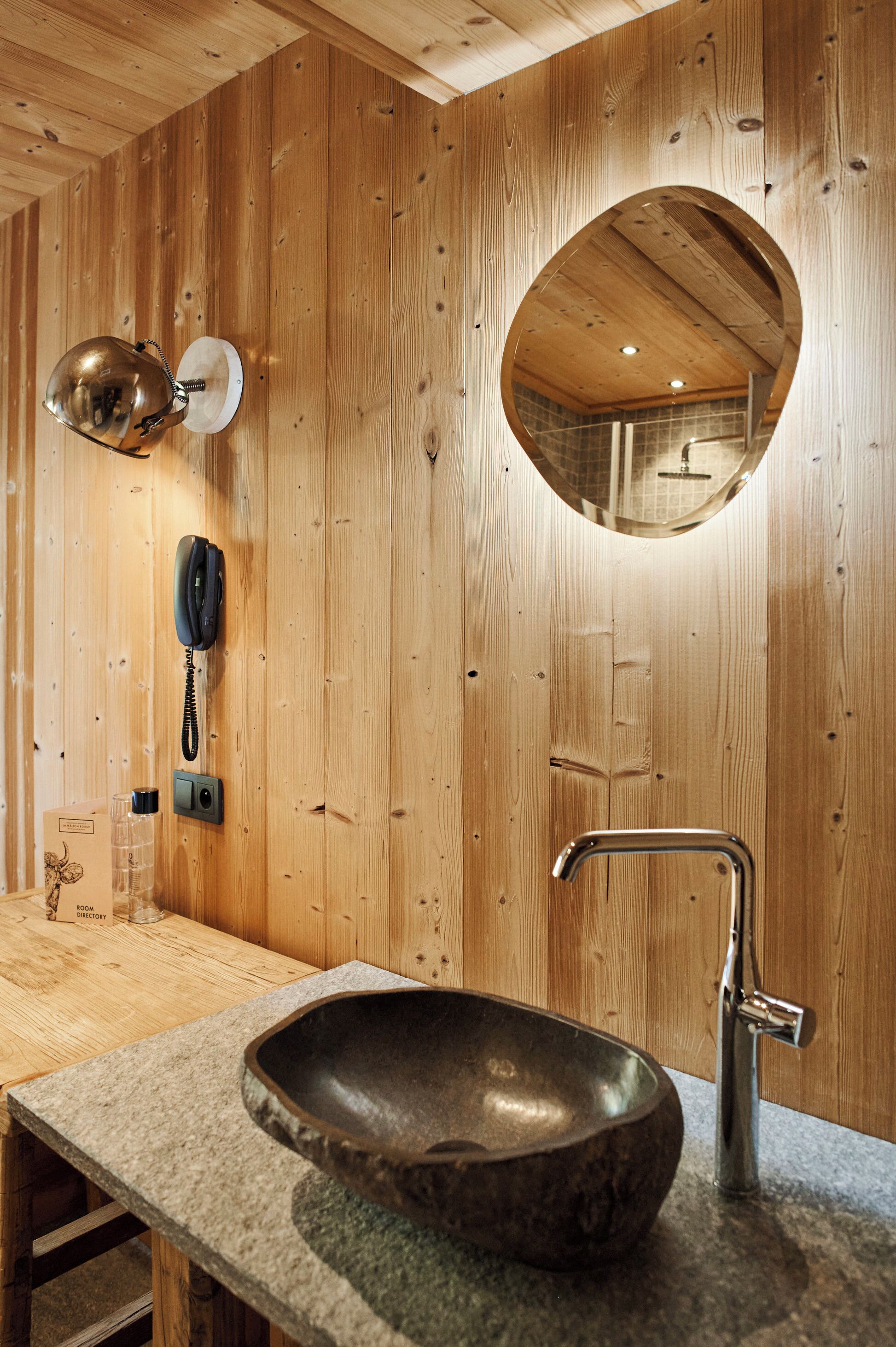 Un interior de madera con un lavabo de piedra, un espejo y un teléfono.