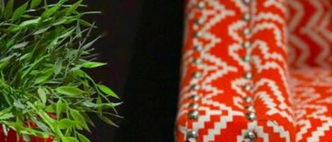 Revista com fotos de viagens sobre uma mesa, ao lado de um sofá vermelho estampado.