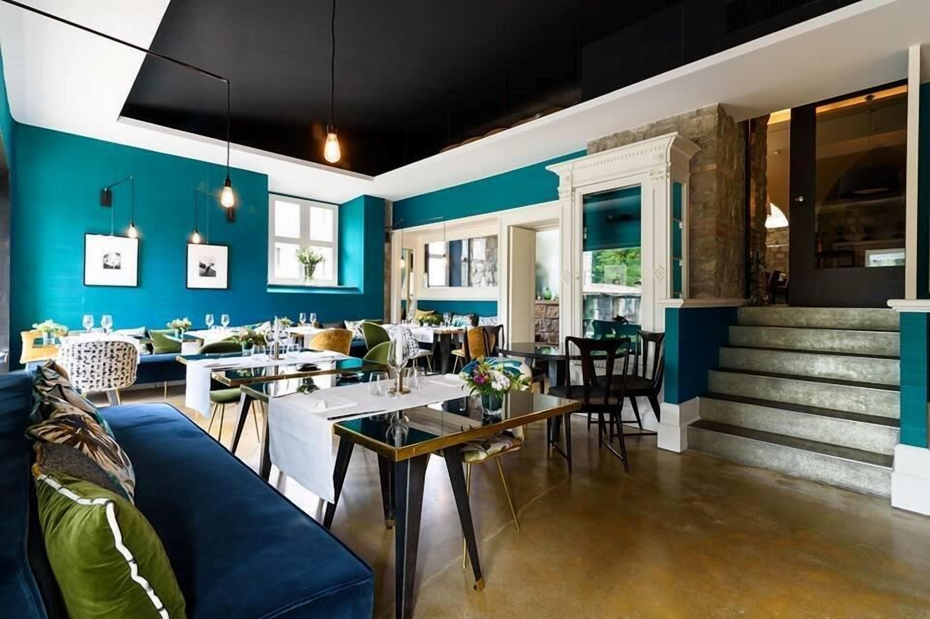 A dining area with teal walls, a blue sofa, and a staircase with stone steps.