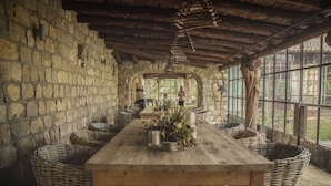A rustic dining area with a long wooden table, wicker baskets, and stone walls. - Aquapetra Resort and Spa (Telese)