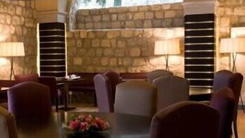 A dining area with stone walls, a large arched window, and multiple tables and chairs.