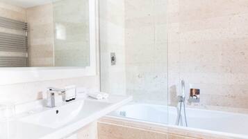 Ein modernes Badezimmer mit zwei Waschbecken, einer Duschkabine aus Glas und einem großen Spiegel.