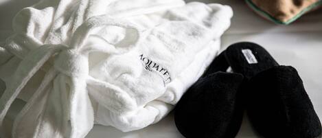 Un albornoz blanco y zapatillas negras sobre la cama.