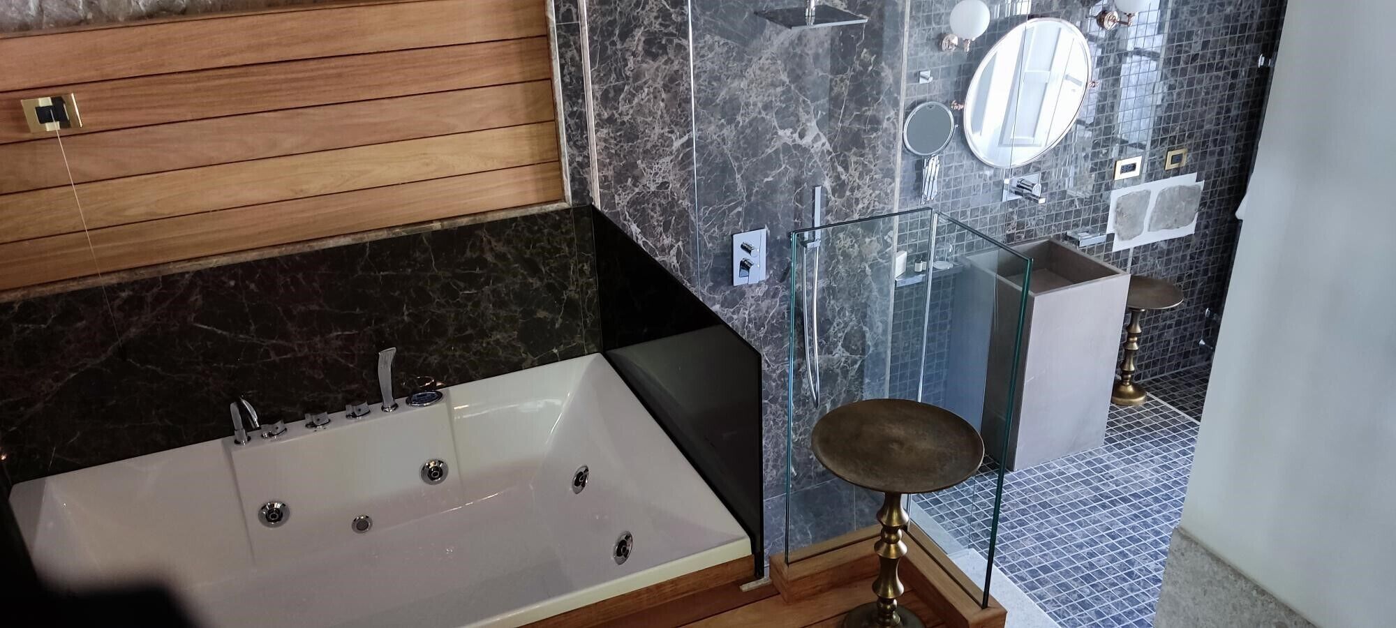 Ein modernes Badezimmer mit einer großen Badewanne, einer gläsernen Duschkabine und einer Wand mit Marmorfliesen.