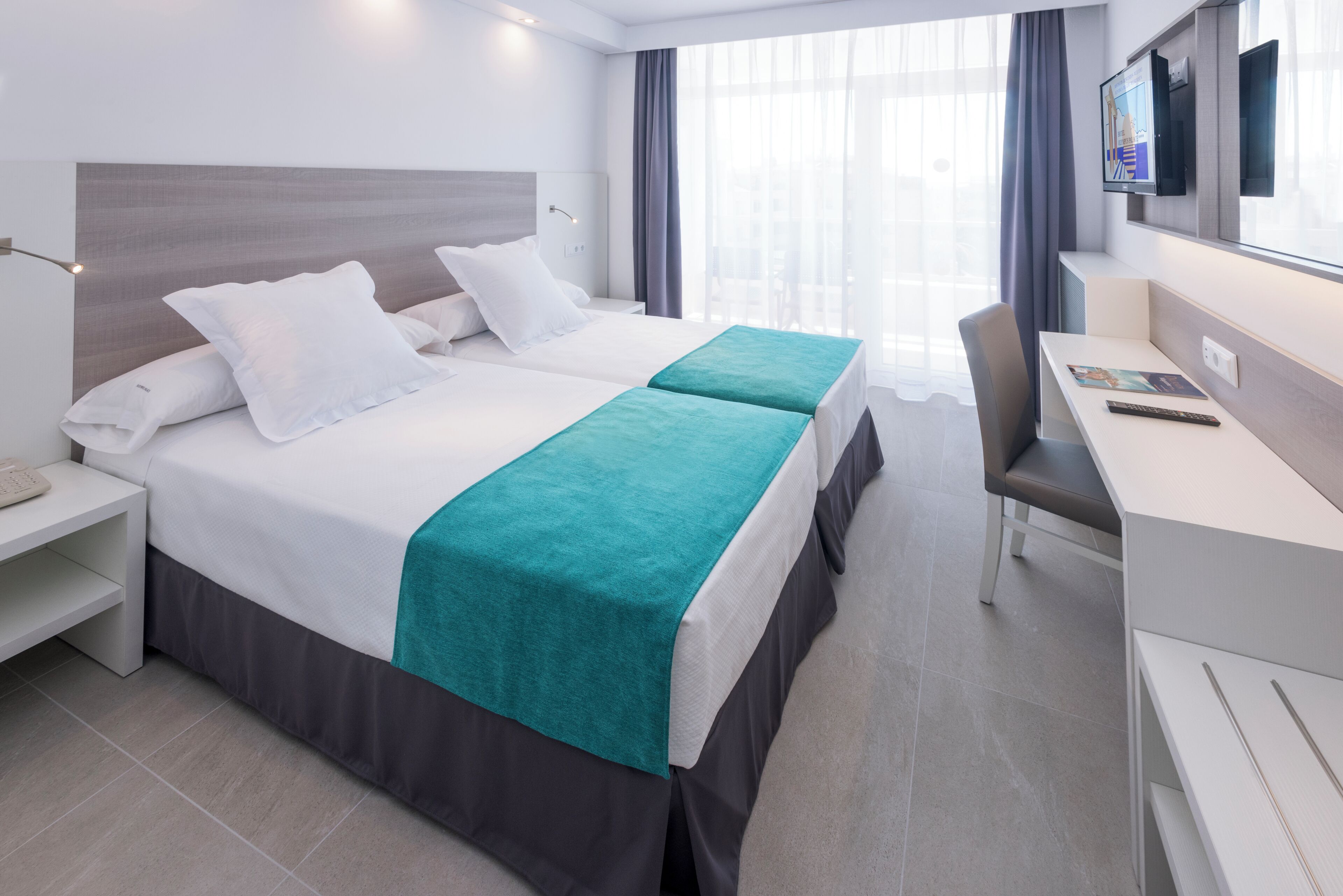 Et moderne hotelværelse med en stor seng, et skrivebord og et fjernsyn.
