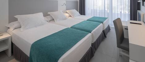A hotel room with two beds, a desk, and a TV.