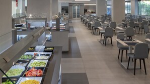 A buffet area with various food options and a seating area with tables and chairs. - Olympus Palace (Salou)
