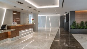 A modern hotel reception area with a marble floor, wooden reception desk, and a large sign reading "Olympus Palace". - Olympus Palace (Salou)
