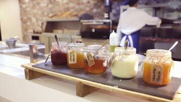 A selection of jars with labels on a wooden board, likely containing condiments or preserves, in a commercial setting.