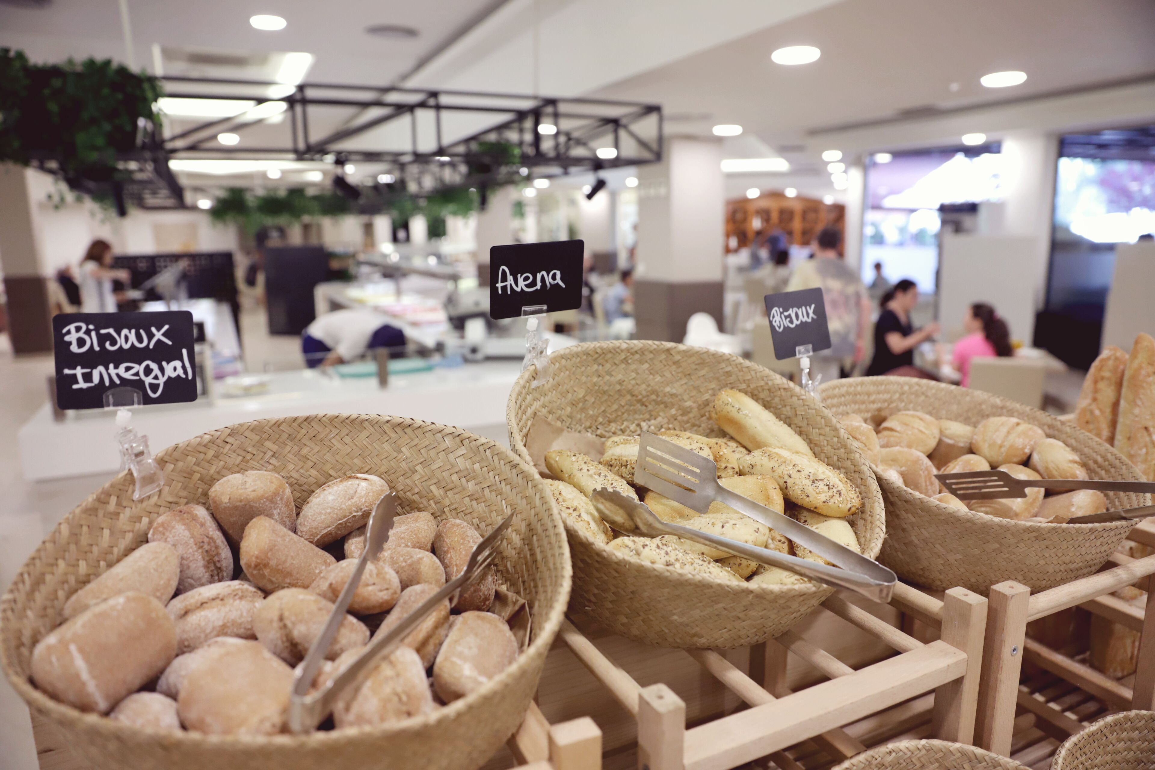 A bakery display with baskets of bread and pastries, labeled with 'BiJoux Integral' and 'Avena'.