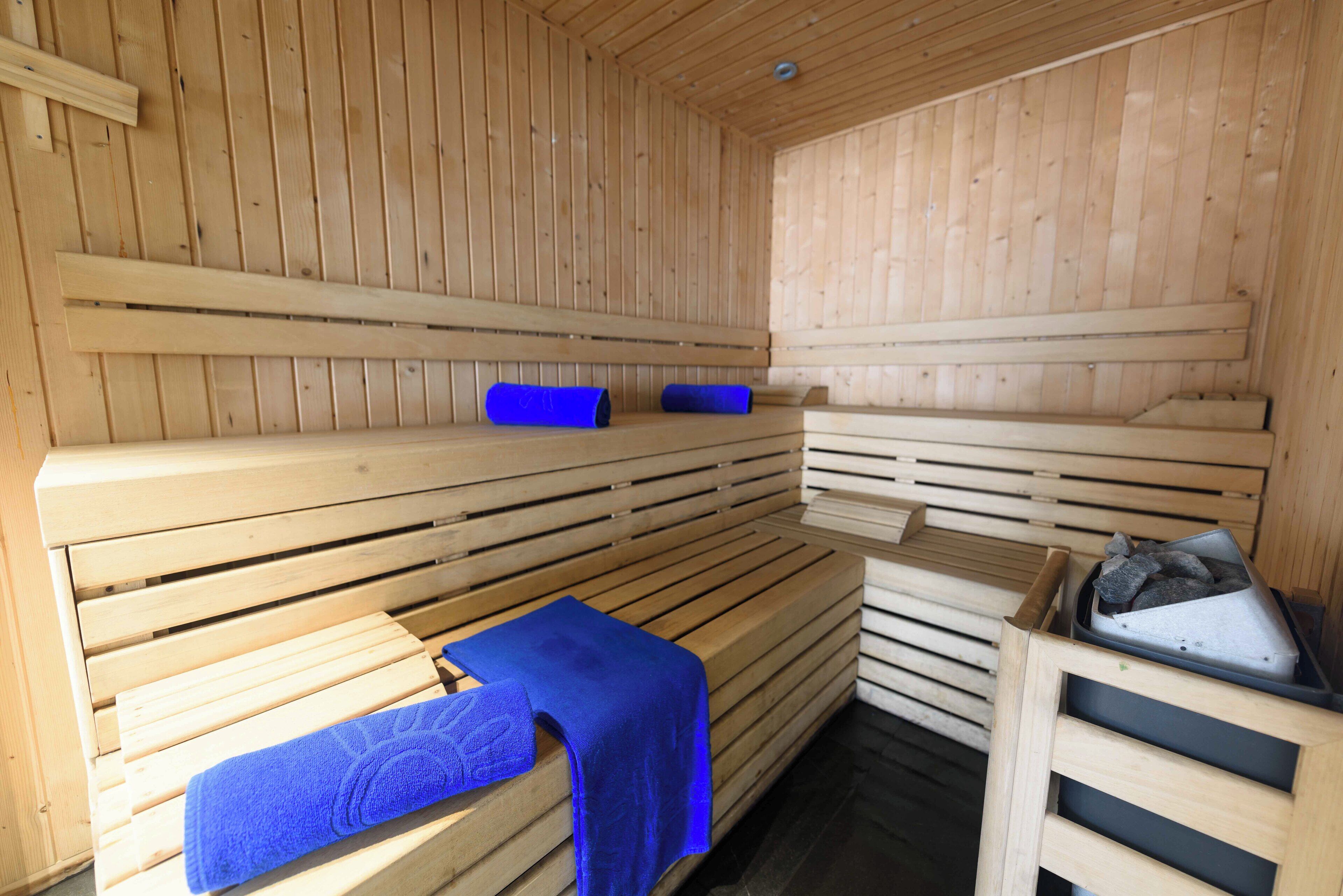 A sauna with wooden benches and benches, some with towels.