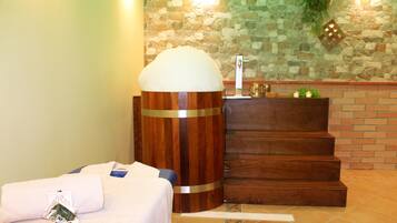 A bathroom with a stone wall, a wooden stool with a white object on top, and a brick wall with a wooden counter.