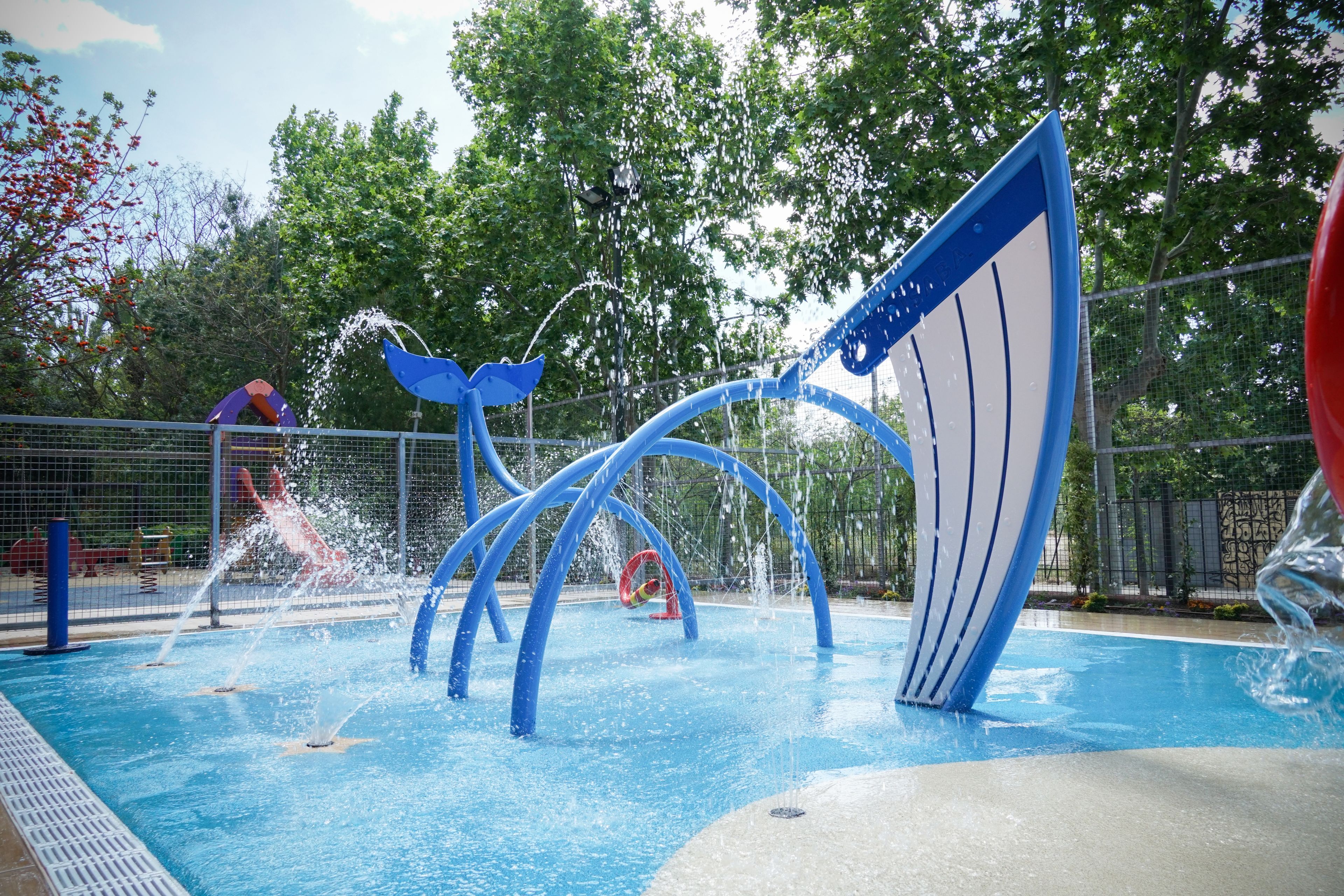 Un parc aquatique doté d’attractions aquatiques bleues et rouges, notamment une piscine à vagues et un toboggan aquatique.