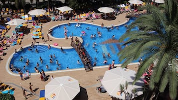 Relax by the pool surrounded by sun loungers and umbrellas, with lounge chairs and shaded seating areas nearby.