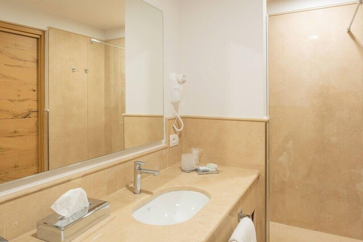 Une salle de bain équipée d’un lavabo, d’un miroir, d’un porte-serviettes et d’un sèche-cheveux.