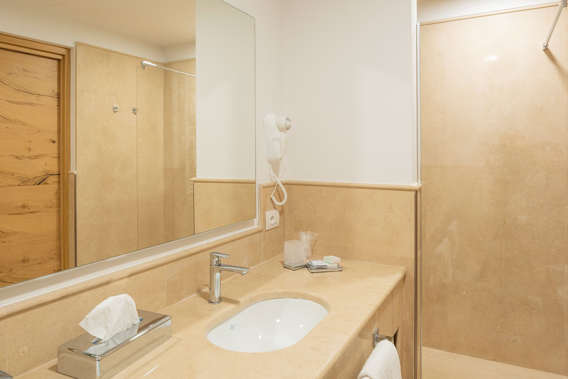 Une salle de bain équipée d’un lavabo, d’un miroir, d’un porte-serviettes et d’un sèche-cheveux fixé au mur.