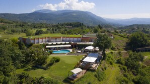 A resort with a swimming pool, outdoor seating, and a view of mountains.