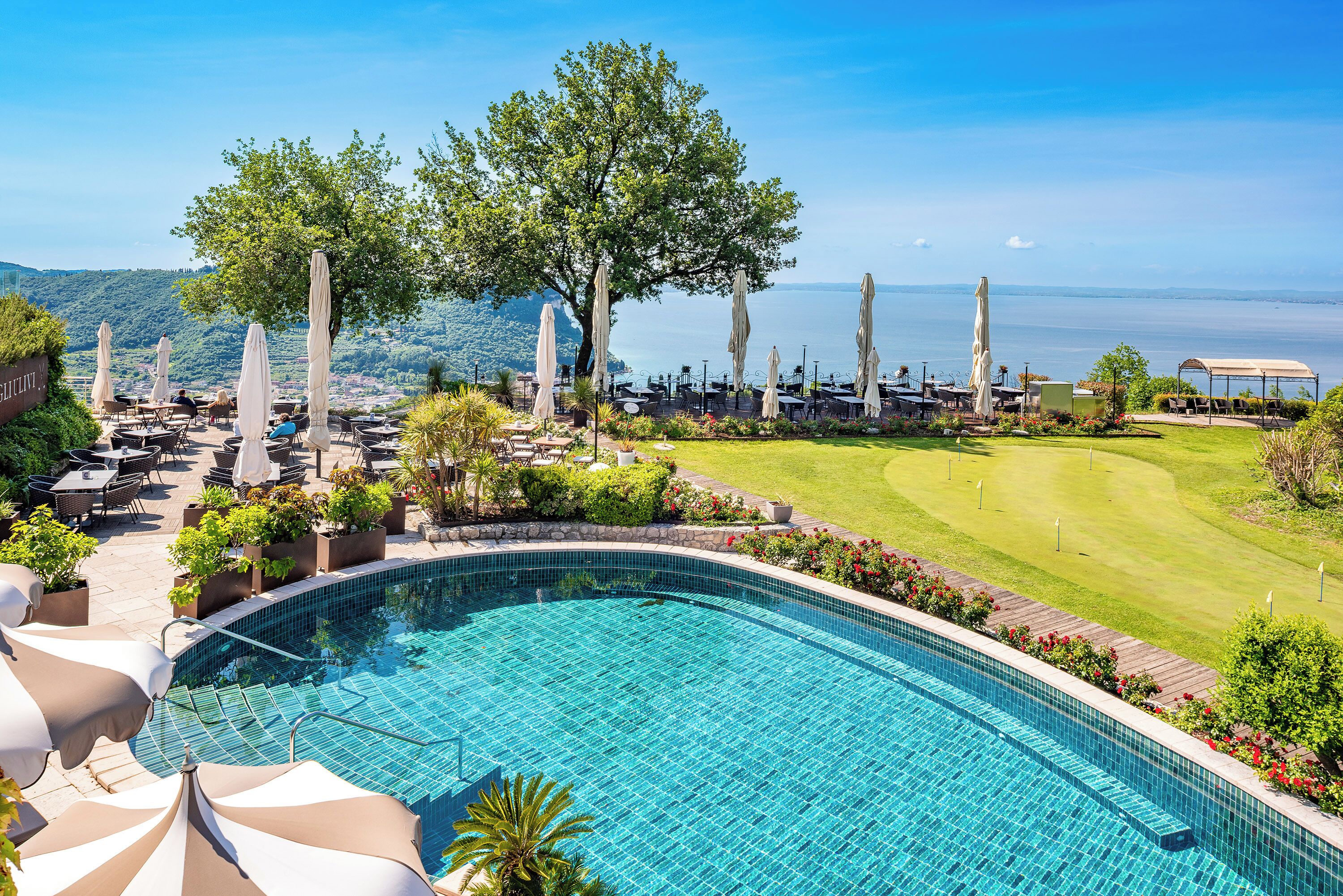Un espace aménagé au bord de la piscine, offrant une vue sur un terrain de golf et un plan d’eau.