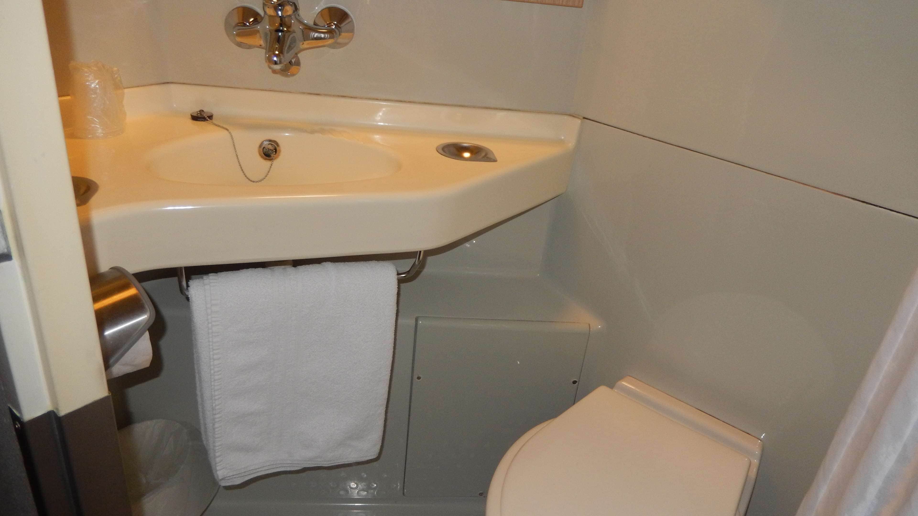Un baño con un lavabo blanco, un inodoro y una toalla colgada en la pared.